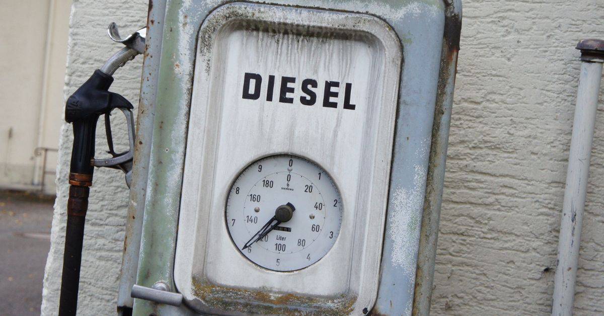 Rusty diesel pump and gauge mounted on weathered exterior wall.