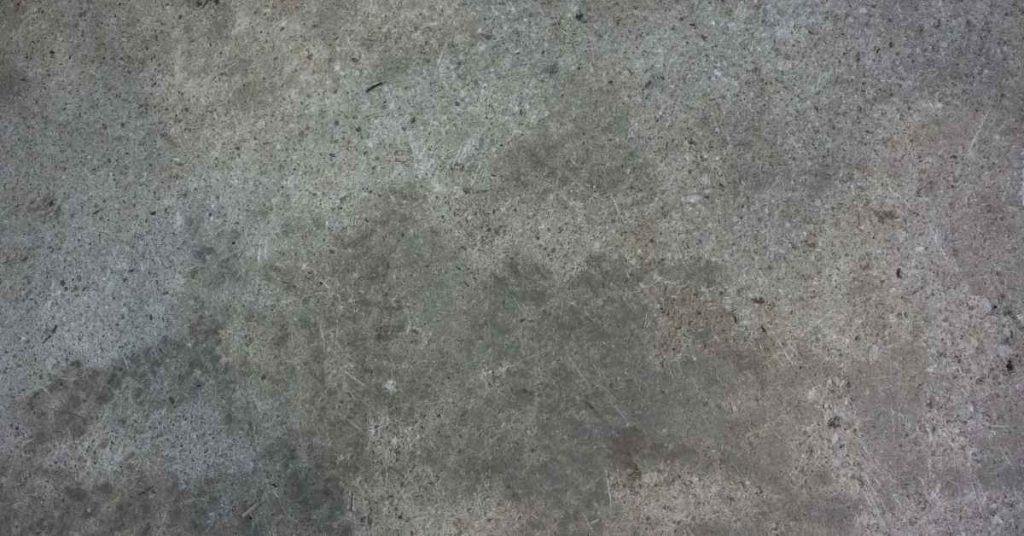 Rough concrete surface with blotchy stains and texture variations.