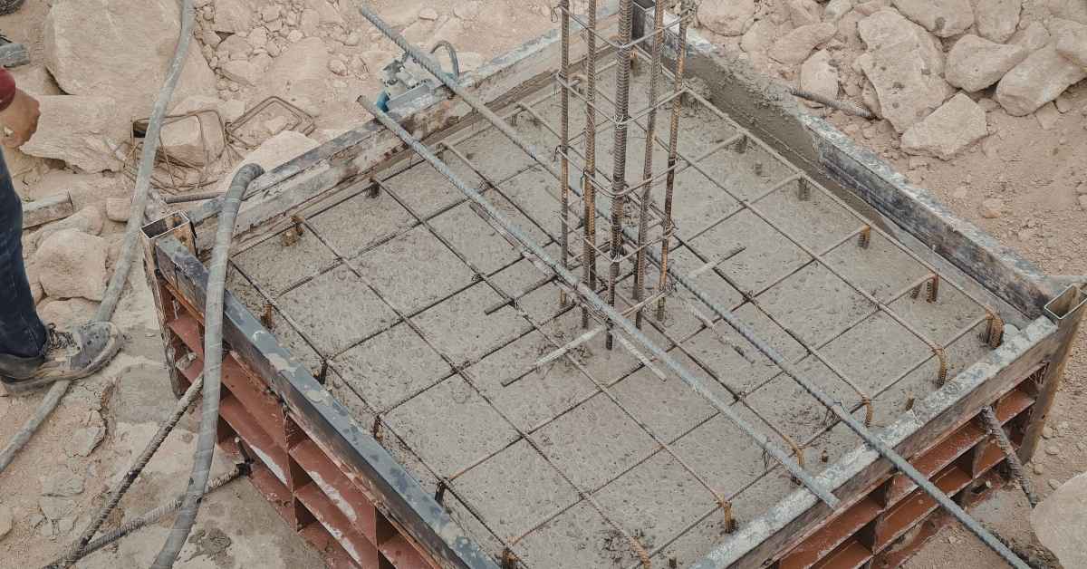 Rebar grid within square concrete formwork awaiting curing.