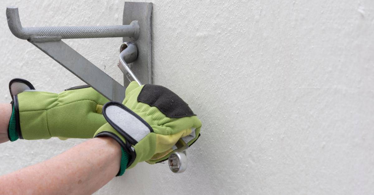 Sleeve anchor and mounting bracket being installed into concrete wall.
