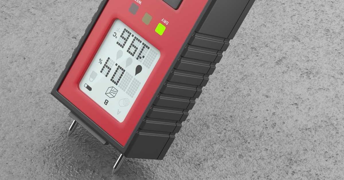 Red moisture meter on concrete slab displaying moisture reading.