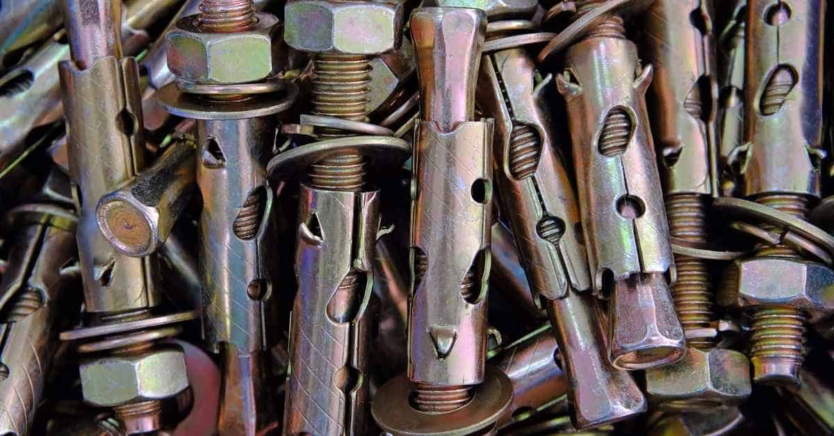 Pile of zinc-coated wedge anchor bolts with hex nuts.
