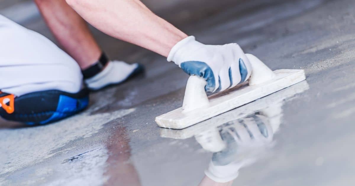 Worker trowels a concrete overlay on a wet floor
