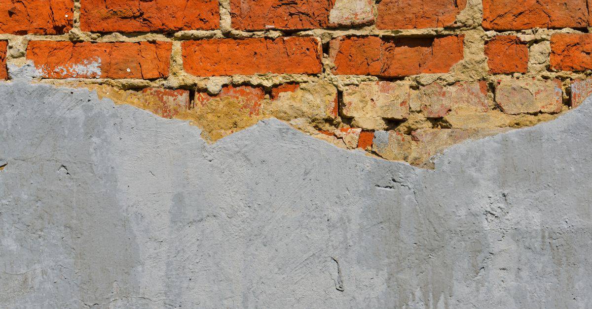partially repaired plaster peeling exposing brick underneath