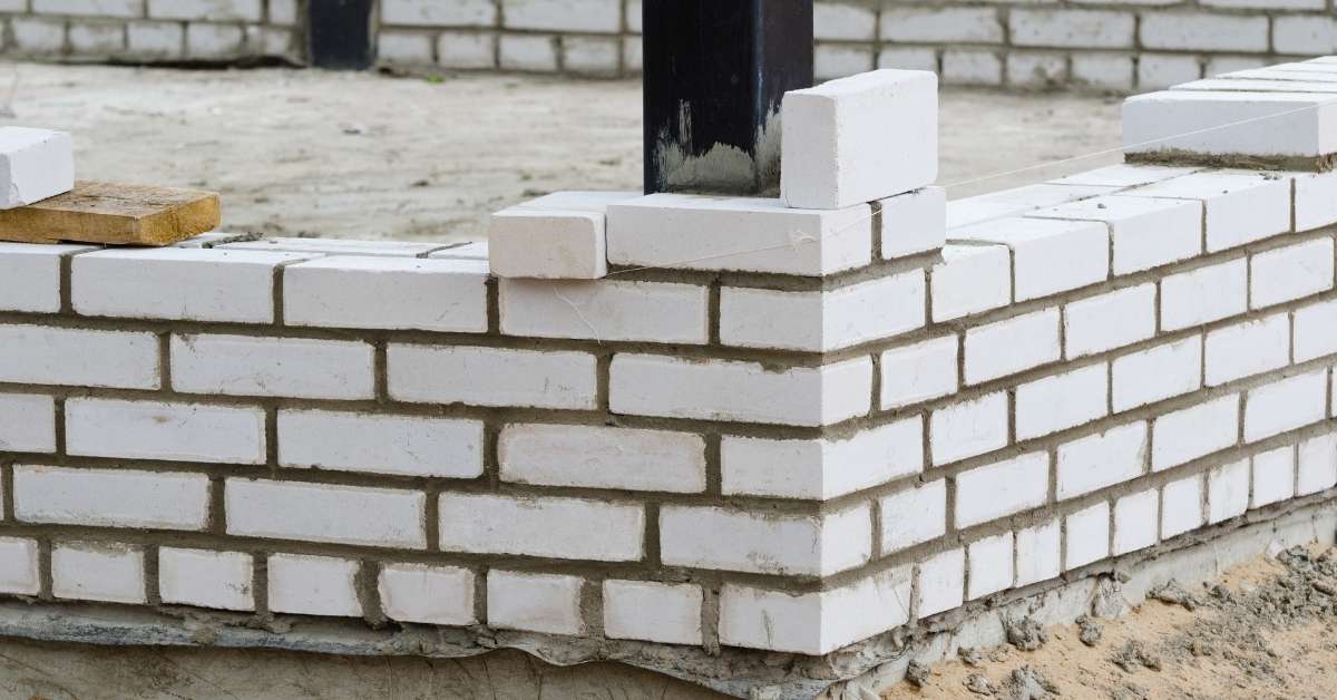 White brick wall corner under construction with exposed mortar