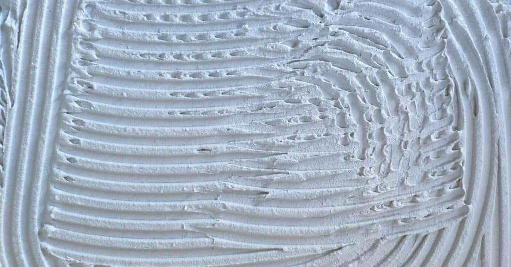 Close-up of white tile adhesive with combed lines