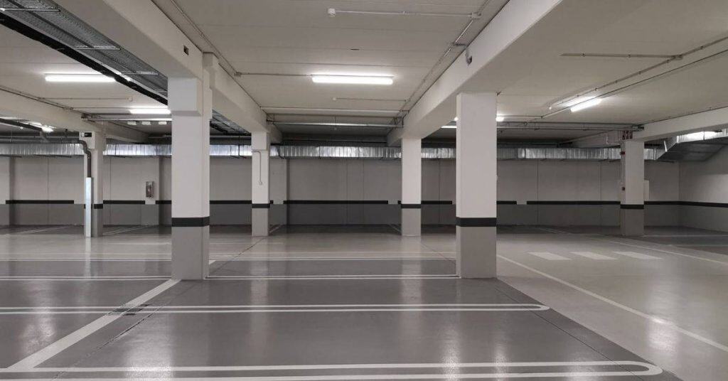 Empty indoor concrete parking garage with columns and marked spaces
