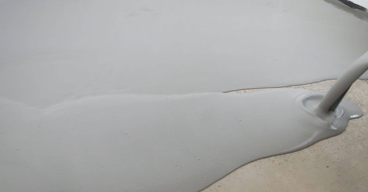 Wet concrete being poured onto floor surface