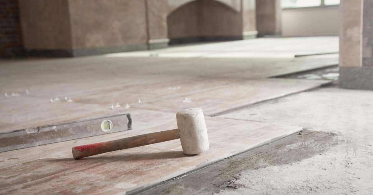 Rubber mallet and level on partially installed tile floor