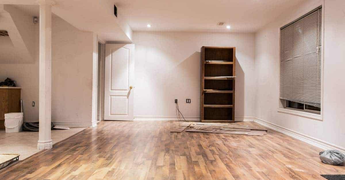Empty basement room with laminate flooring and wooden shelf