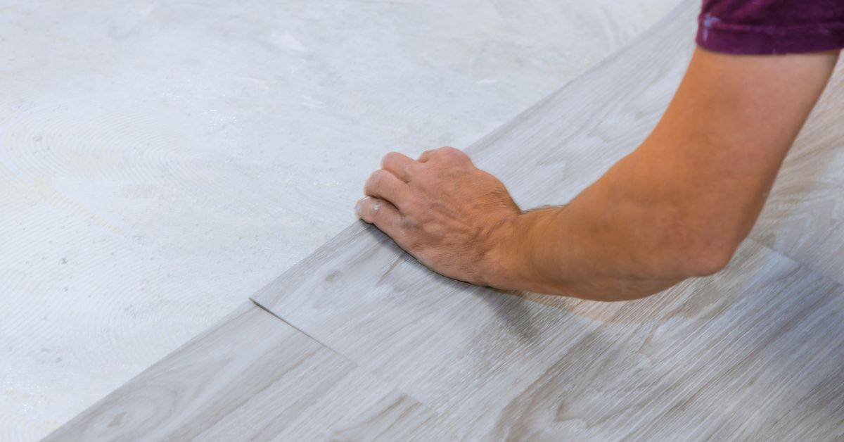 Hand installing light gray vinyl flooring planks