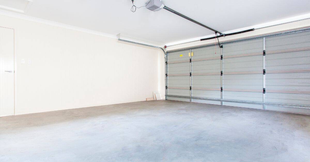 Empty residential garage with concrete floor and closed door