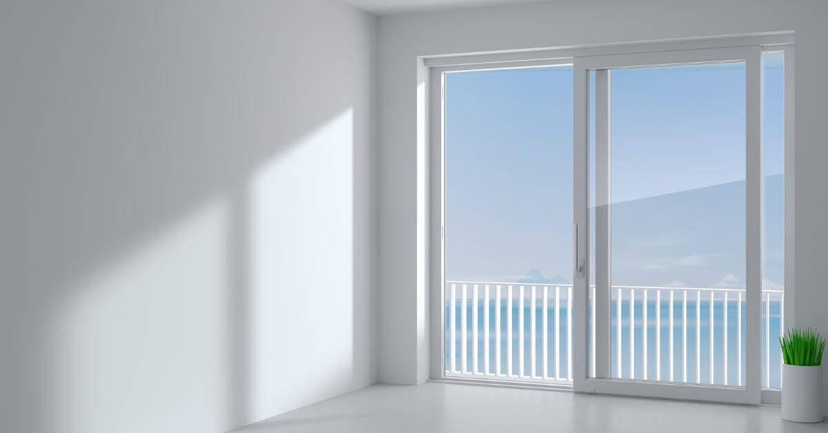 Empty white room with large sliding glass door and small plant