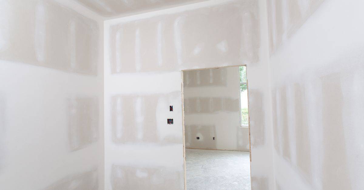 Unfinished drywall interior room with window and doorway