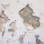 Wall surface with peeling paint and exposed damaged areas