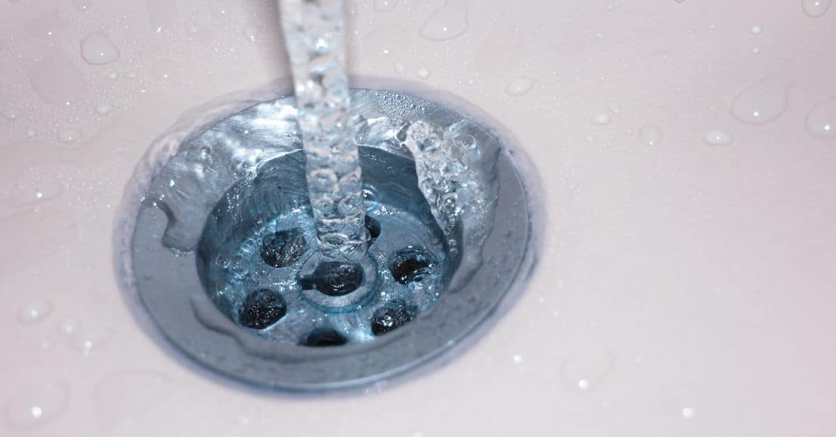 Close-up of water flowing into a metal sink drain