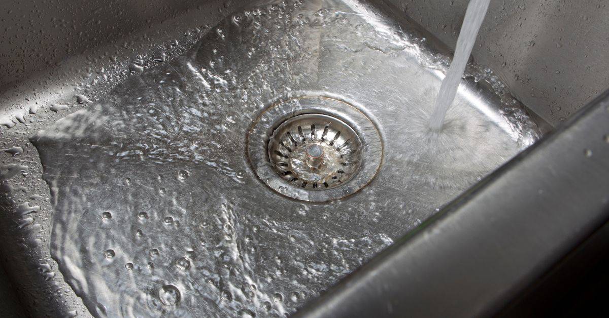 Water flowing into stainless steel kitchen sink drain