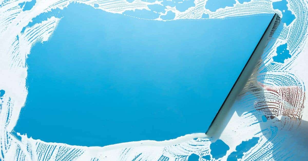 squeegee cleaning blue soapy window glass