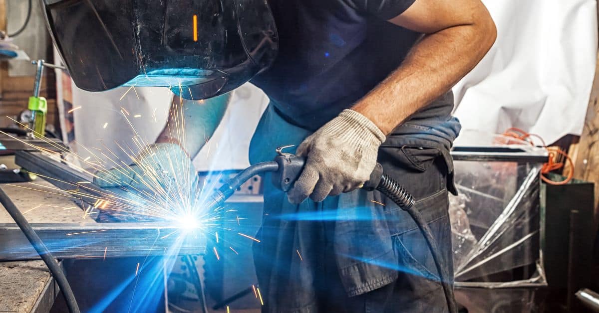 Person welding metal with protective helmet and gloves