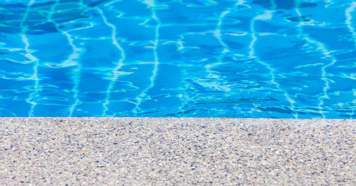 Close-up of pool edge with exposed aggregate finish and water