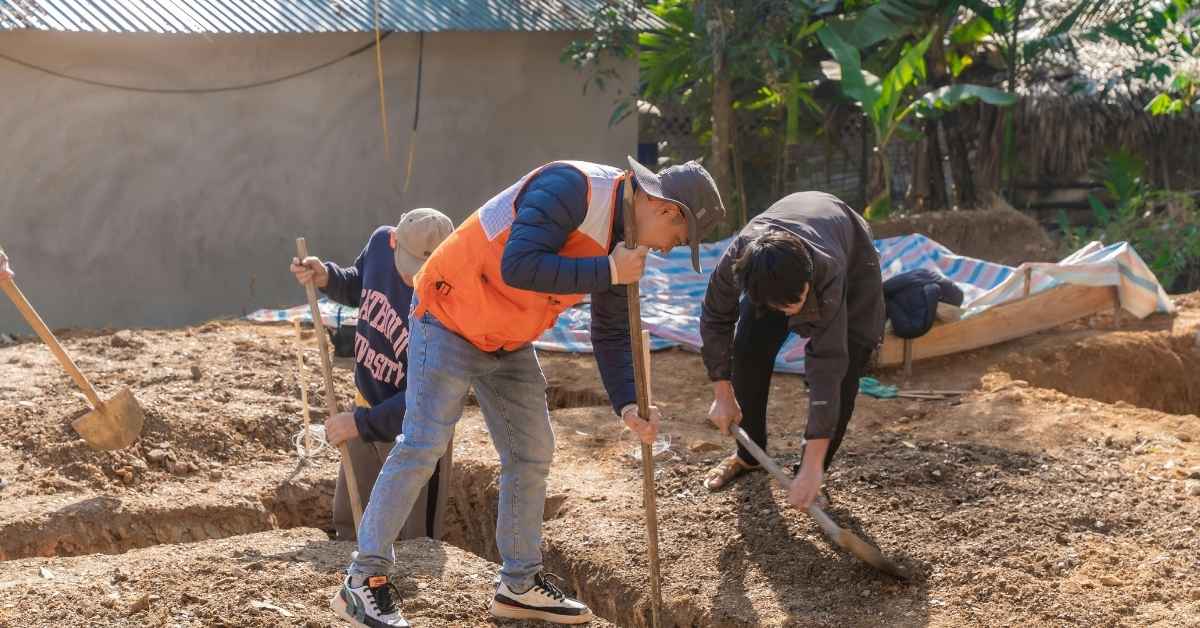 Three men digging trenches in outdoor soil