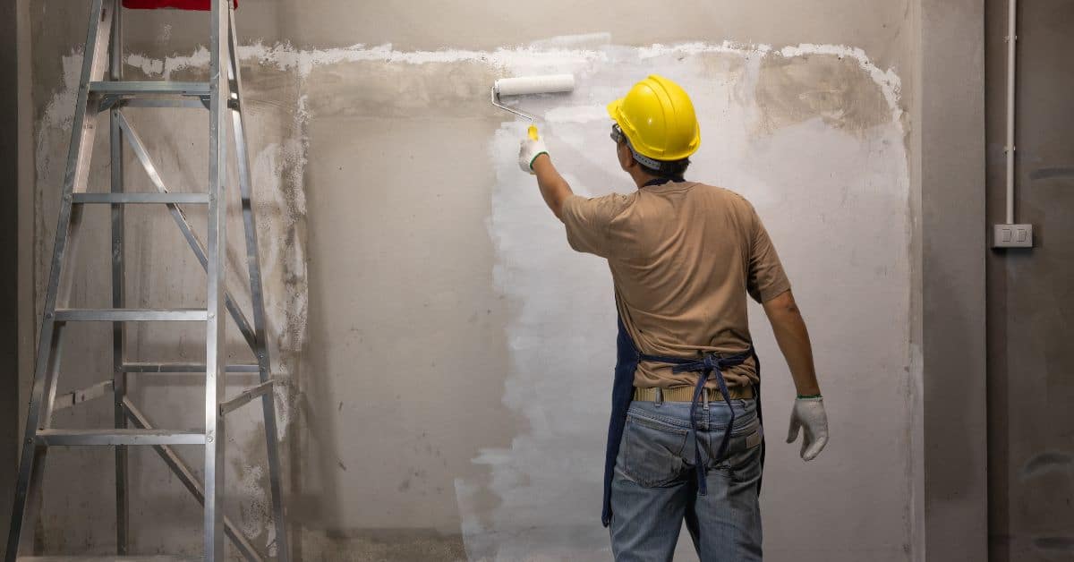 Man in yellow helmet painting wall with roller