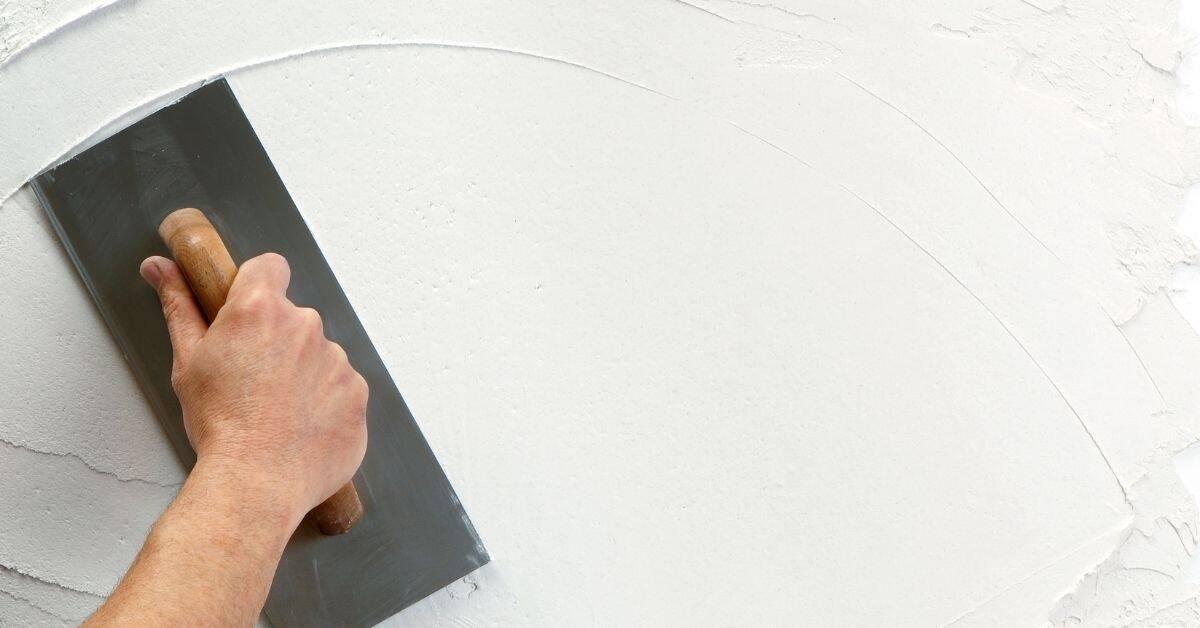 Hand applying white lime plaster with trowel