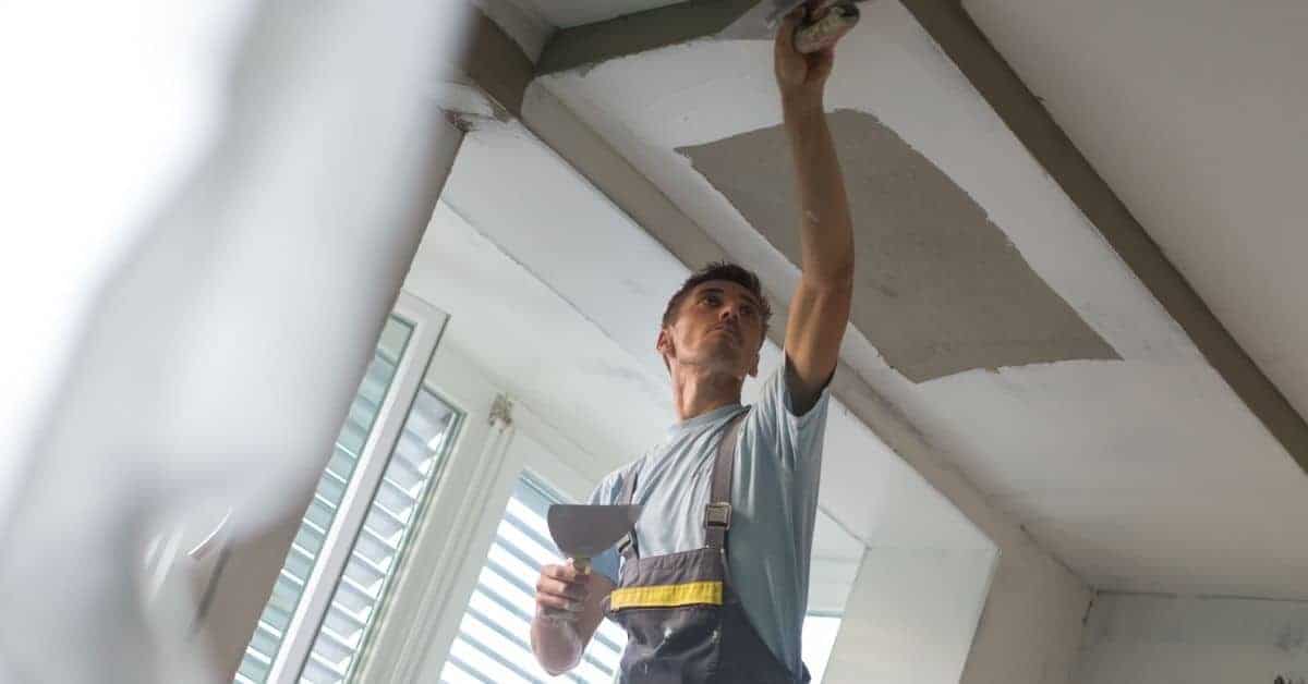 Man applying plaster patch to ceiling with spatula