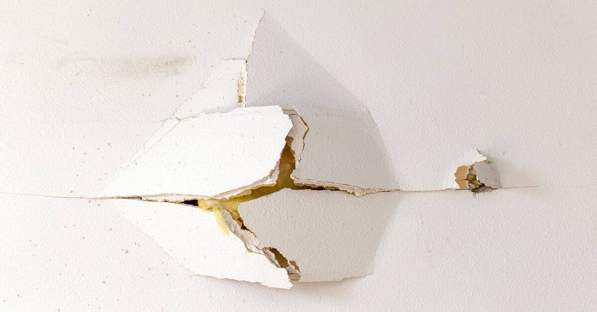 Cracked and peeling damaged plaster on wall