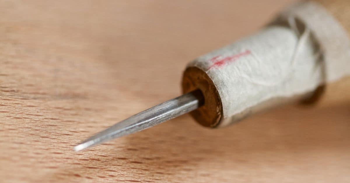 Close-up of a pointed metal plaster scratch tool tip