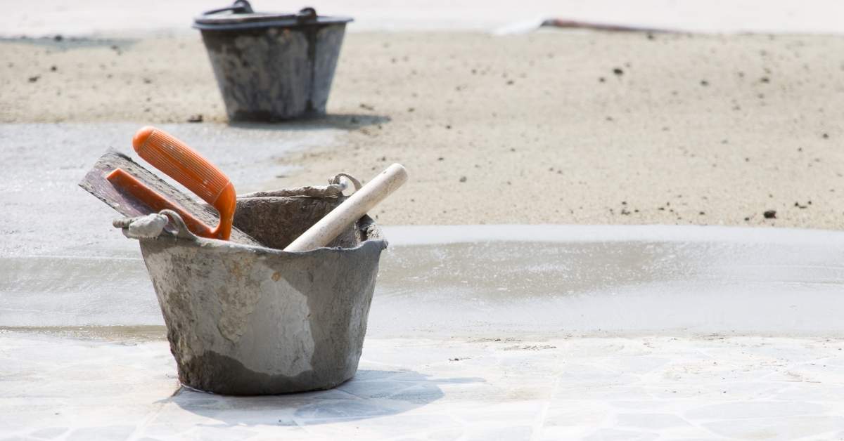 Bucket with plastering tools on concrete ground