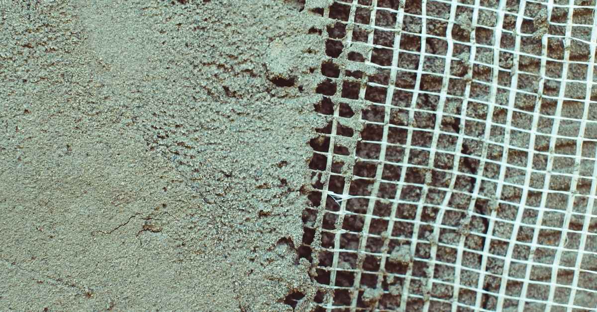 Stucco partially applied over white fiberglass mesh on wall surface