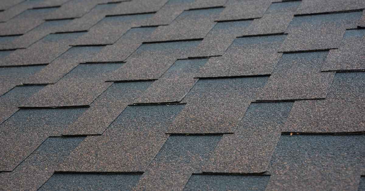 Close-up of dark asphalt roof shingles arranged in overlapping pattern
