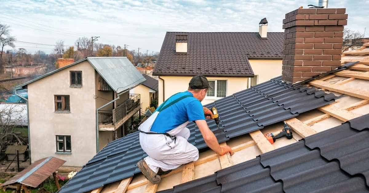 Man installing metal roof tiles on sloped roof