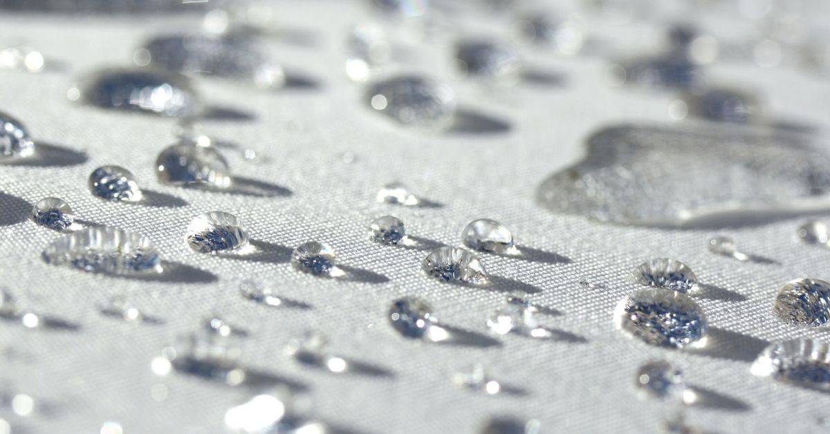 Water droplets beading on white polyester fabric surface
