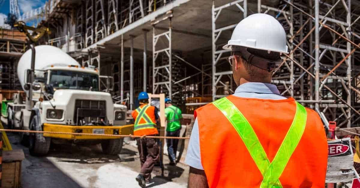Construction workers and cement mixer truck at building site