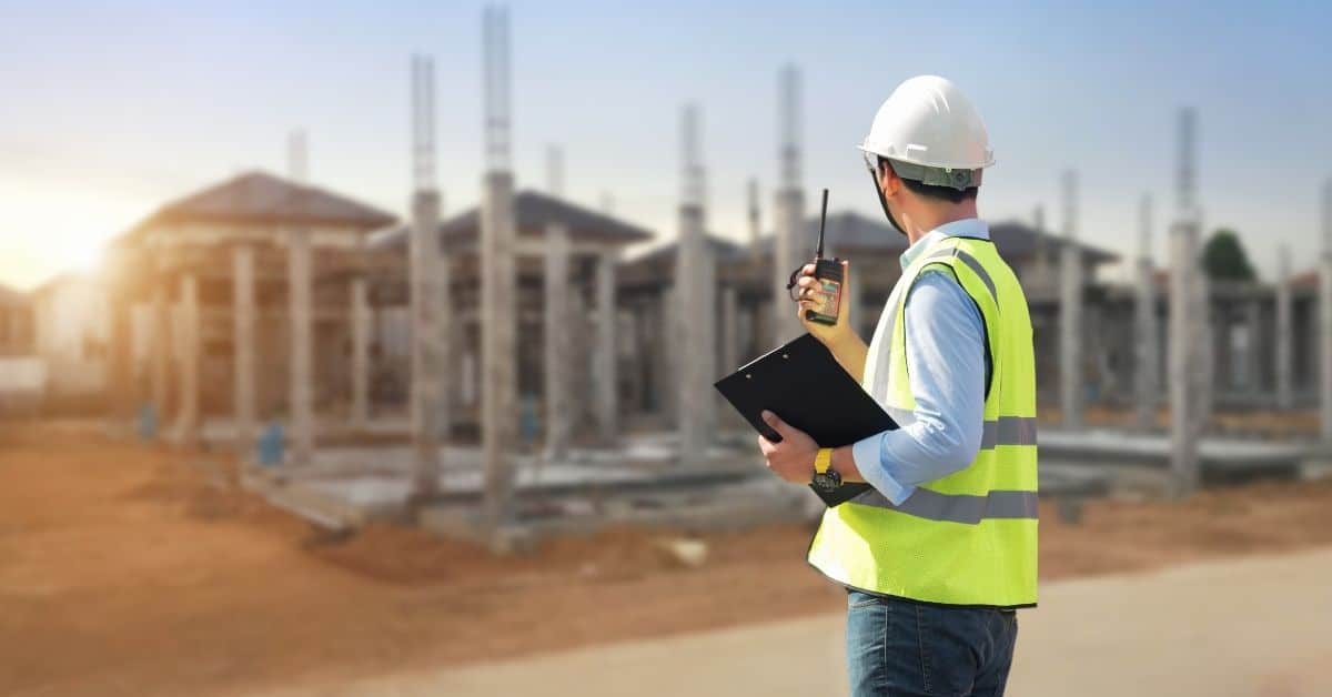 Man in safety vest and helmet holding clipboard and walkie talkie
