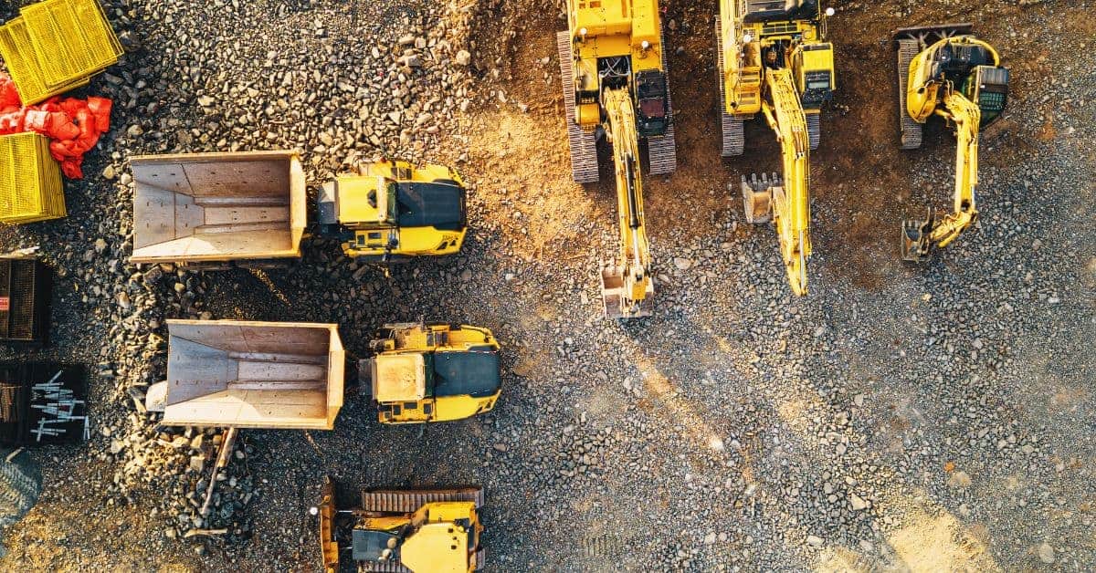 Yellow heavy construction vehicles parked on rocky ground