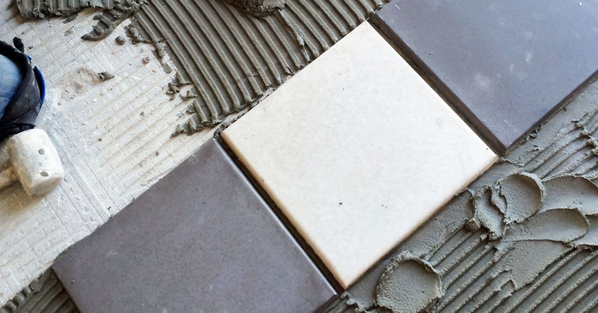 Close up of ceramic tiles being installed with adhesive spread