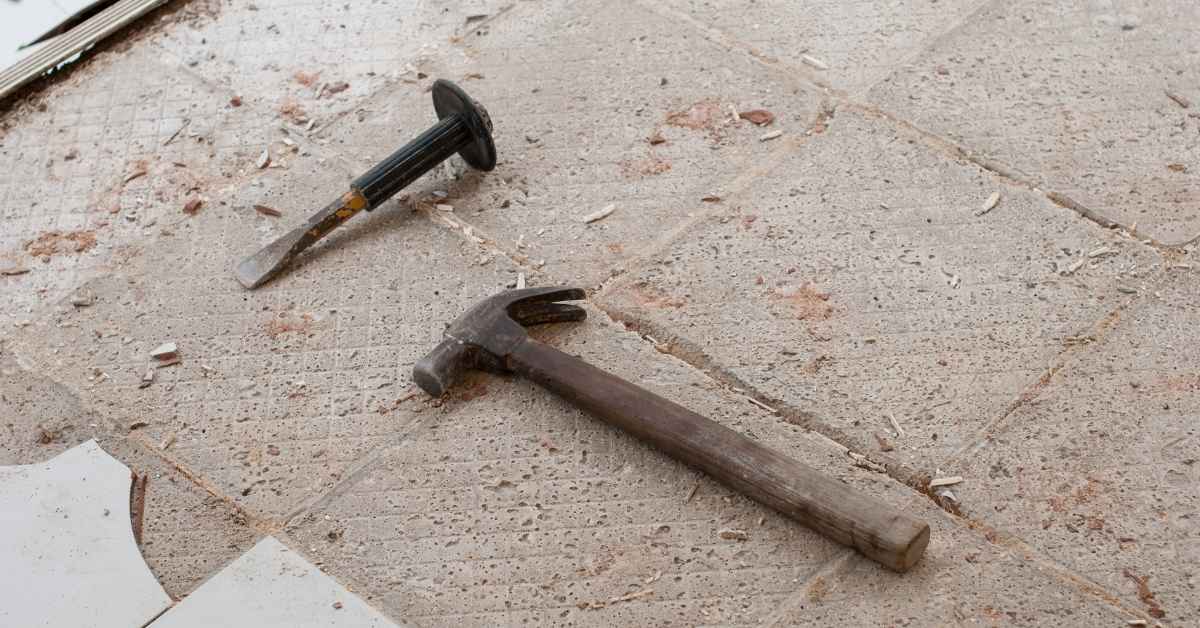 Hammer and chisel on broken tiled floor