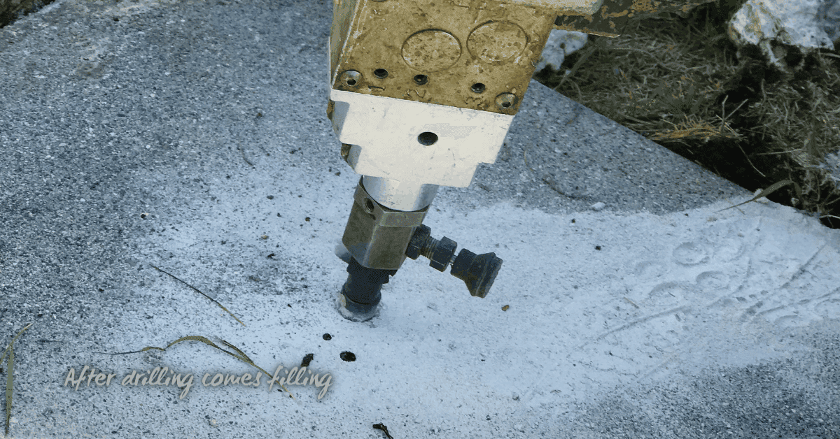 drill bit in concrete slab with dust around hole