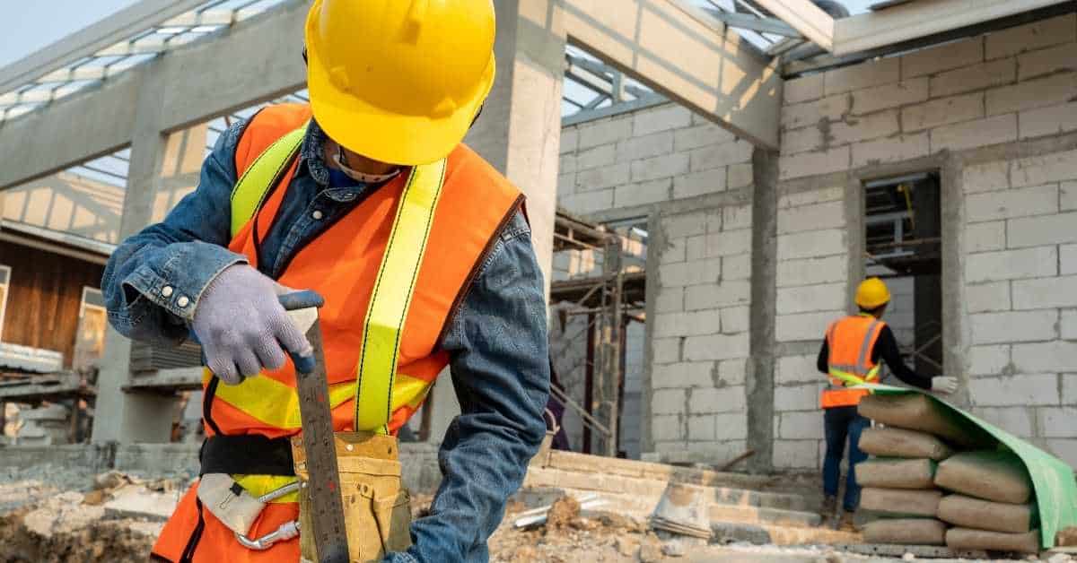 Construction worker in safety vest and helmet using tool
