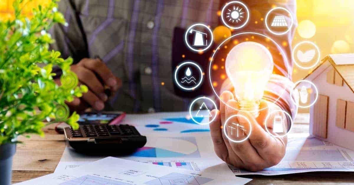 Person holding glowing light bulb with calculator and papers