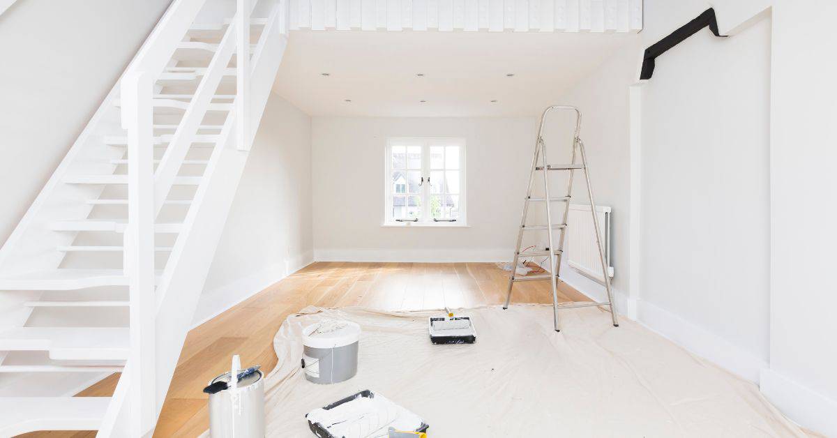 Empty room with white walls ladder paint cans and rollers