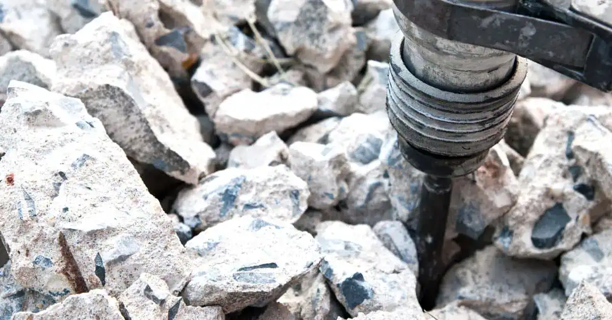 Jackhammer breaking concrete into debris pieces