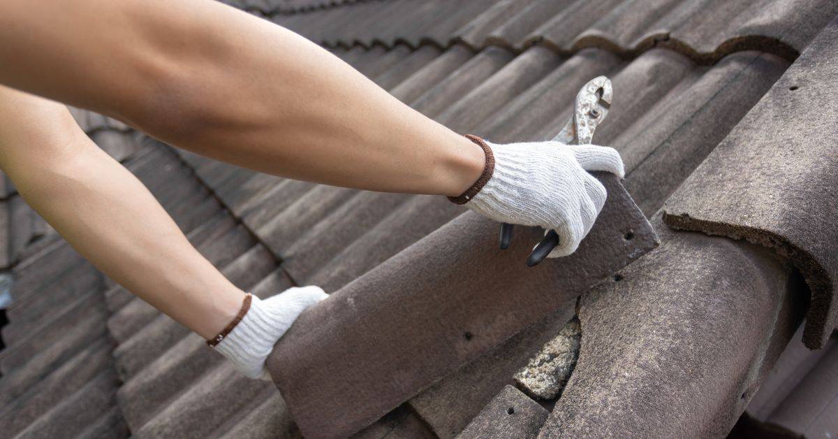 Hands in white gloves removing damaged roof tile