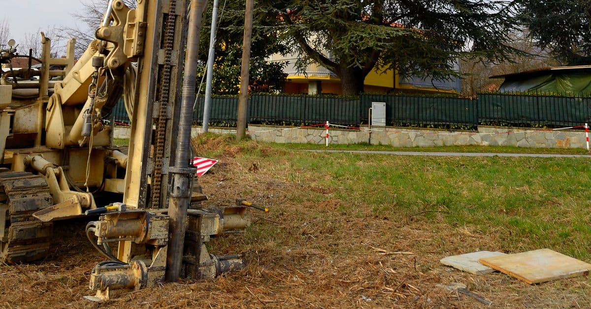 Large drilling rig machine on grassy field near fence