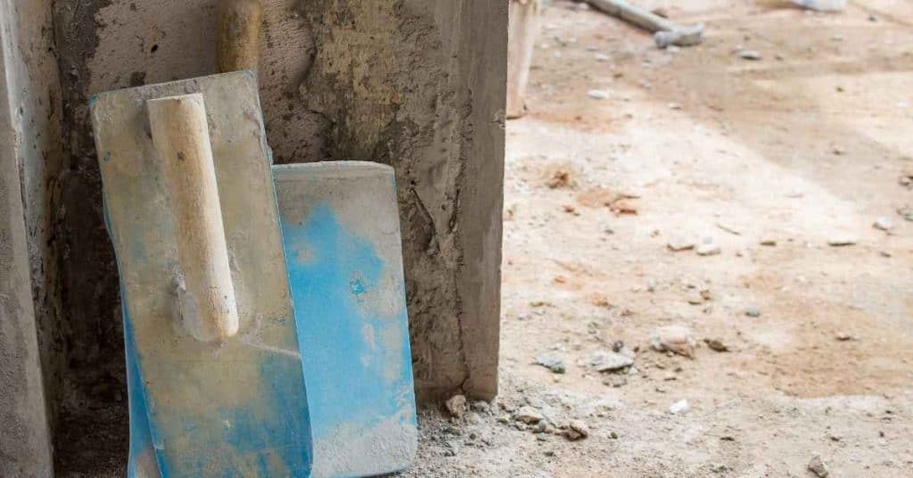Two plaster trowels leaning against rough plastered wall