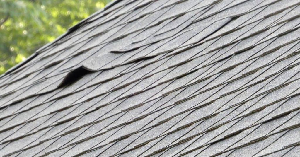 Asphalt roof shingles with visible buckling and rippling