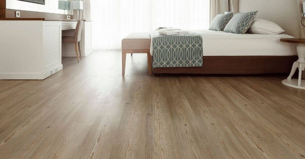 Bedroom with wood-look vinyl flooring and neutral bedding